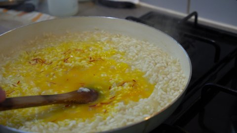 Italian Chef cooking yellow saffron risotto, stirring the saffron in the creamy rice.