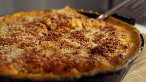 Fork dig in a cast iron skillet filled with mac and cheese, a classic American dish, baked in the oven with crispy breadcrumbs on top