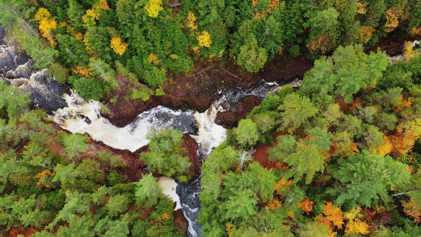 Beautiful look down aerial flying over Brownstone Falls at the junction of the Tyler Forks and Bad river with colorful fall foliage and red rock lining the river banks in autumn at Copper Falls park.