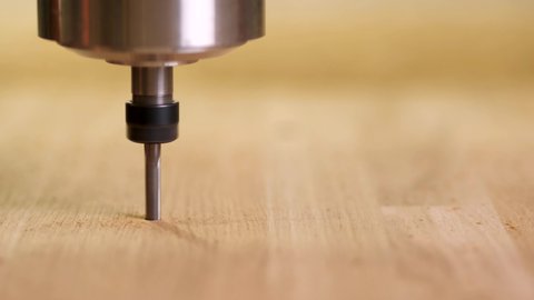 The head of the cnc wood router moves quickly in a straight line, drilling the board. Automated Wood carving