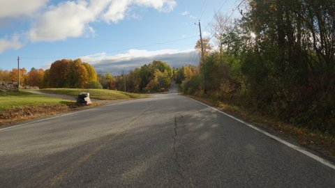 POV Driving a car on asphalt road with colorful trees in autumn. Sunny day with sun beams