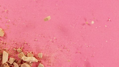 Makeup crushed mineral powder crumbles on pink background, fashion make-up concept. Super slow motion