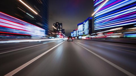 Beautiful motion timelapse of high speed drive on the night. Front view from the windscreen to the road with other cars and night city with skyscrapers and neon lights.