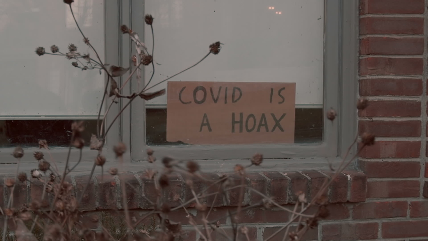 A covid hoax sign outside in window