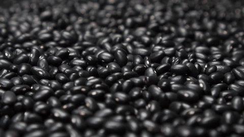 Black beans falling into a heap with a close up rotation. Selective focus. Slow motion