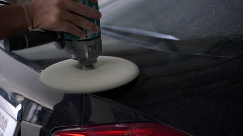 Black car body polishing with polisher tool in auto service. Waxing car after car wash. Car body work - 4K
