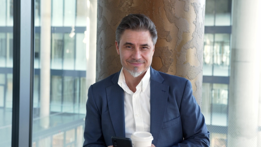 Business portrait - confident older businessman in modern corporate office.