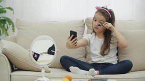 4k video of little cute girl looking in the mirror and doing make up.