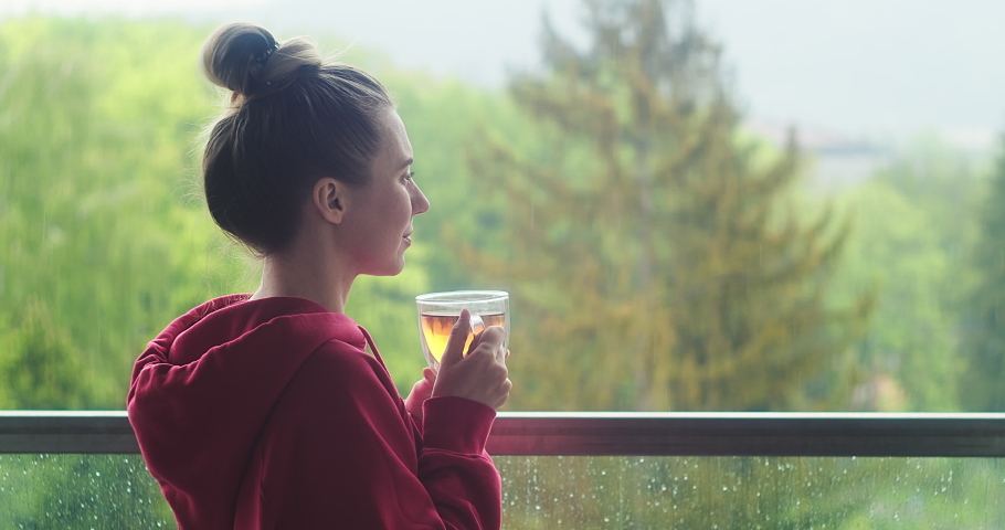 Woman drinks tea a cup, and relax on terrace at home in autumn rainy day. Health care, authenticity, sense of balance and calmness. Work from home. 4K Video | Shutterstock HD Video #1062797959