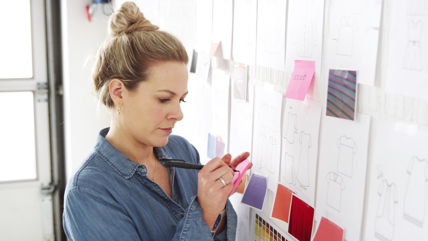 Female Business Owner Putting Adhesive Note On Designs And Swatches On Wall In Fashion Business Royalty-Free Stock Footage #1062799489