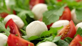 pour olive oil on caprese salad with mini mozzarella, tomatoes cherry and arugula