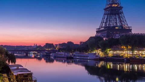 Eiffel Tower and the Seine river night to day transition timelapse before sunrise, Paris, France. Morning view from Bir-Hakeim bridge with reflections on water