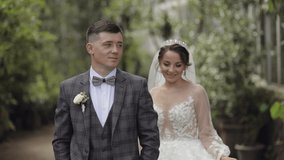 Newlyweds. Lovely caucasian bride and groom walking in park. Embracing, hugs. Happy wedding couple family. Man and woman in love. Bride in gorgeous wedding dress. Bridegroom in jacket. Slow motion