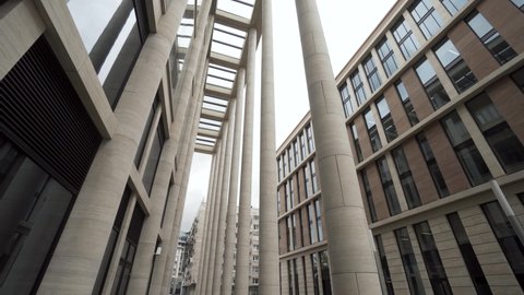 Facade of a building with marble columns. Action. Bottom view of a modern architectural complex, new building with light beige pillars and larg windows.