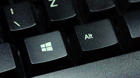 Krakow, Małopolska, Poland - November 2020: Finger pressing the Microsoft Windows 10 operating system key on a black, desktop pc keyboard, macro, extreme closeup. OS logo button