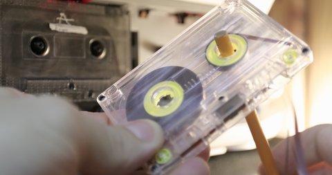 Manually rewind a cassette tape with a pencil. Man rewind a cassette tape.