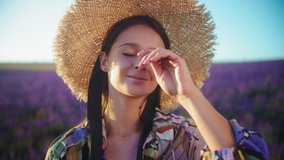 Portrait of a young woman in a lavender field. Young woman in a straw hat in the summer enjoying nature in Provence. Slow motion 4K video