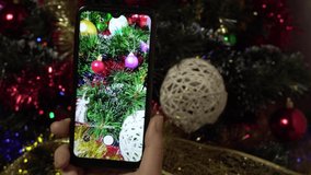 A female hand makes a photo of a Christmas elegant tree using a smartphone.Photo of a Christmas tree for social networks.4k