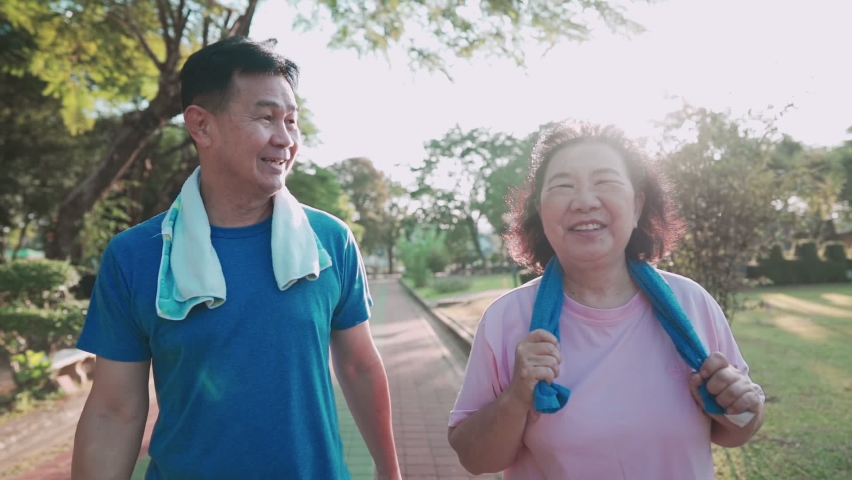 Asian senior couple walking together in side recreation public park, healthy retirement lifestyle, relationship goal, happy smiling middle age couple exercises, family outdoor activities on sunny day Royalty-Free Stock Footage #1062831340
