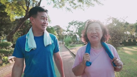 Asian senior couple walking together in side recreation public park, healthy retirement lifestyle, relationship goal, happy smiling middle age couple exercises, family outdoor activities on sunny day
