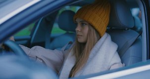 Portrait of beautiful woman in hat look at camera driving car. View of woman drives a automobile. Casual face adult lady window attractive. Close up. Slow motion