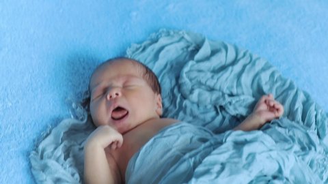 Newborn crying baby boy. New born child tired and hungry in bed under blue knitted blanket. Children cry. Bedding for kids. Infant screaming. Healthy little kid shortly after birth