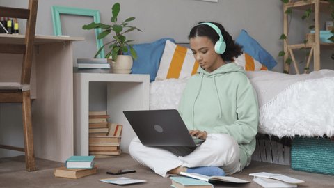 African american teen school girl distant school or college student virtual remote e learning using laptop in bedroom looking at camera. Distance education classes, studying online at home concept.