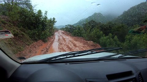 Car moves on the dirty road in Bolivian jungles. POV from driver's seat
