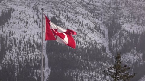 Canadian flag waving in wind with snow covered mountains 4k