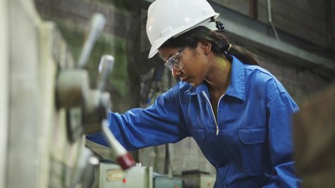 candid asian female Professional engineering wearing uniform and safety goggles Quality control, maintenance, check in factory, warehouse Workshop for factory operators