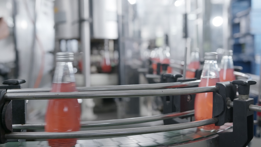 Bottling factory machinery prodution line - red juice bottling line for processing and bottling juice into bottles. Selective focus industrial technology business concept Royalty-Free Stock Footage #1062846823