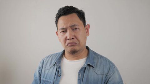 Young asian men wearing jacket mocking with funny face, Sticking out his tongue, over grey background
