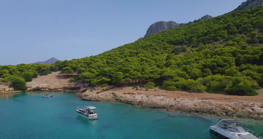 Ascending drone shot of moored yachts and catamarans on a beautiful bay with many green trees