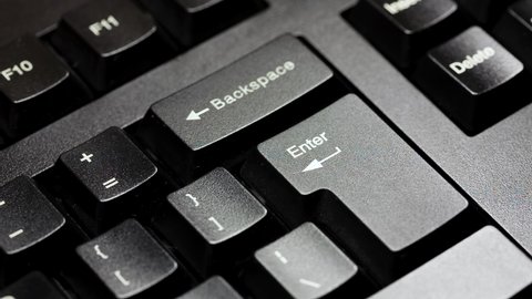 Finger presses the enter key on a modern black desktop pc keyboard. Hitting enter on computer keyboard, extreme closeup, detail. Accepting, sending chat message, digital confirmation simple concept 