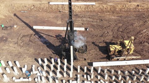 High impact weight drives pile deep into the ground. Aerial view of pile driver rig at construction site. High quality 4k footage