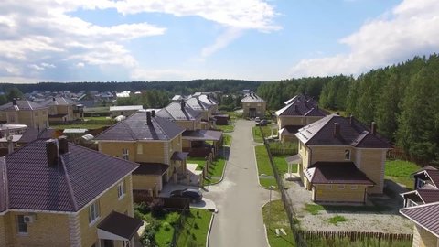 Aerial drone footage over the summer street. Modern luxury houses. Aerial flying over the residential area. Asphalt roads and sidewalks
