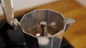Moka pot brewing caffeine beverage in home kitchen.Traditional Italian coffee maker machine brews energetic drink in the morning.Fresh caffeine drink being brewed on gas burner with zooming videoclip