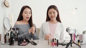 Young two beautiful Asian woman beauty influencers doing cosmetic review online live streaming at home 