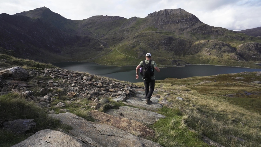 Man walking down stone mountain trail towards Crib Goch and Llyn Llydaw