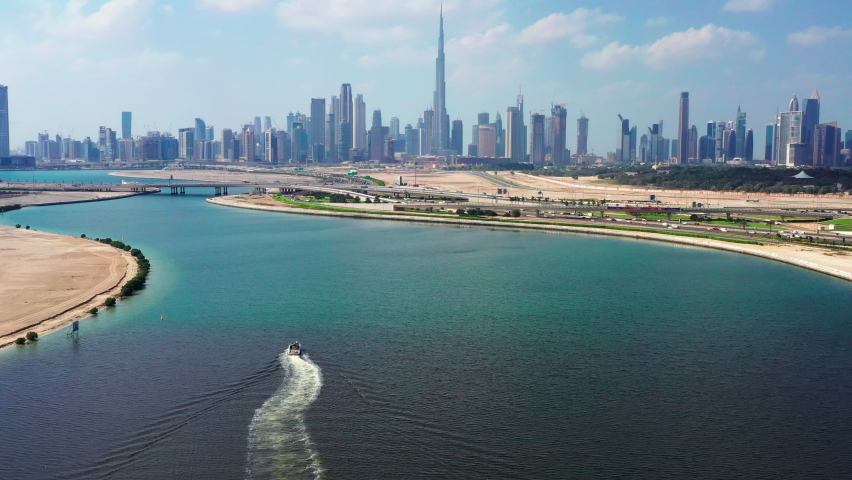 Aerial view of Burj Khalifa and Dubai skyline with yacht sailing in lake towards Downtown Dubai Royalty-Free Stock Footage #1062863302