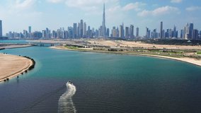 Aerial view of Burj Khalifa and Dubai skyline with yacht sailing in lake towards Downtown Dubai