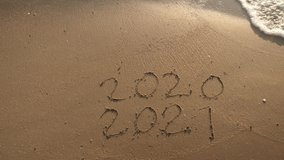 Message Year 2020 replaced by 2021 written on beach sand background. Good bye 2020 hello to 2021 Lapping waves happy New Year coming concept - Powered by Shutterstock - Get 15% off with code: PIKWIZARD15