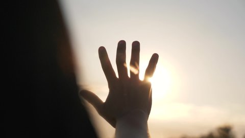 Silhouette of a happy dreaming girl pulls her hand to the sun. Religion helping hand. Happy girl pulls her hand. Prayer in religion. Silhouette of a hand in the sun. Happy girl silhouette at sunset