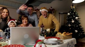 Happy and Excited family greeting their family and friends on Christmas eve using a video call. Some relatives waving and talking to a laptop screen. Social distancing, quarantine.