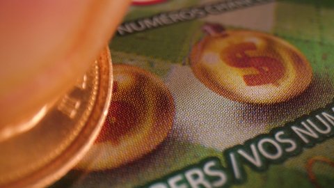 Macro shot of scratching lucky numbers on an instant lottery scratch ticket.