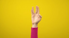 A female hand shows an alien greeting sign. Studio photography on an isolated yellow background. - Powered by Shutterstock - Get 15% off with code: PIKWIZARD15