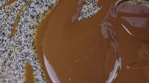 Chocolatier adds melted milk chocolate on granite table for right tempering. confectioner stirring with spatula tempered liquid chocolate. pastry chef at work