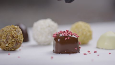chocolatier sprinkles freeze-dried raspberry crumbs on chocolate sweets decorating Exquisite delicious handmade chocolates assortment. luxurious confectionery, Candy manufacturing small business