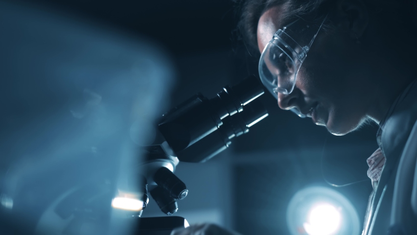 A woman scientist is looking into microscope, biochemical research. Scientific and medical lab instrument. A doctor is search for vaccine to treat diseases in laboratory for medicine study Royalty-Free Stock Footage #1062881113