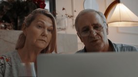 Senior mature adult Caucasian couple having a video call with friends or family on Christmas eve. Holidays celebration during COVID-19 Coronavirus lockdown